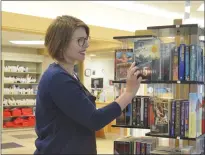  ?? NEWS PHOTO MO CRANKER ?? Medicine Hat Public Library head of marketing services Gillian Reimer organizes the paperback exchange shelves Friday afternoon. The station allows Hatters to give and take paperback books as they please until Aug. 31.