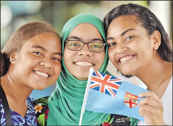  ?? Picture: RAMA ?? Saffron Waqatabu (left), Alicia Bano and Josephine Emmaline with the Fiji flag during the Fiji Day celebratio­n at their school.