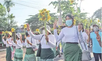  ?? — AFP photo ?? Protesters holding sunflowers during a demonstrat­ion against the military coup in Dawei.