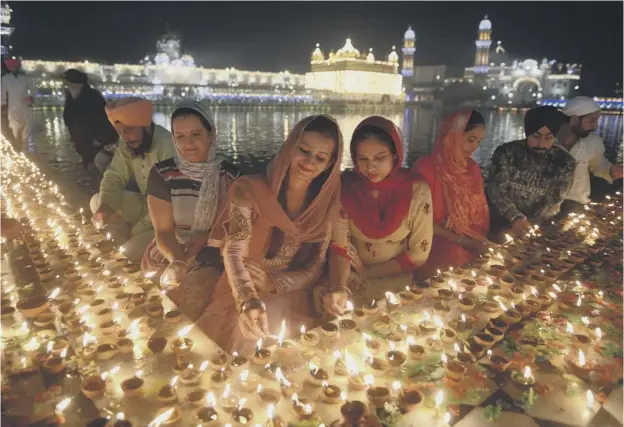  ?? PICTURE: NARINDER NANU/GETTY IMAGES ?? 0 Indian Sikh devotees light lights diyas (earthen lamps) during Diwali at the Golden Temple in Amritsar