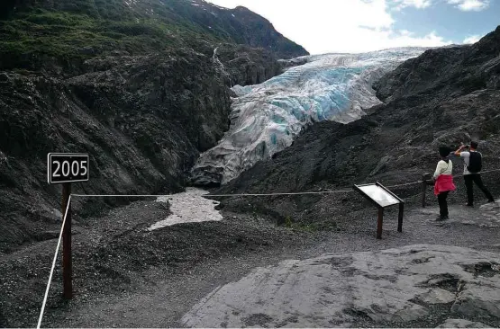  ?? Isabel Fleck/Folhapress ?? Turistas observam a geleira Exit, em parque nacional em Seward, no Alasca (EUA); placa à esquerda aponta até onde o gelo chegava em 2005