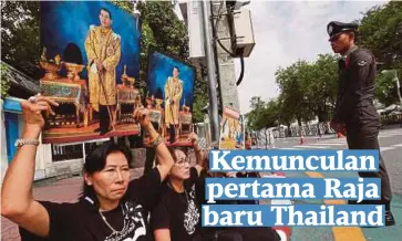  ??  ?? SEKUMPULAN wanita duduk di tepi jalan yang menuju ke Istana Besar di Bangkok semalam sambil menjunjung gambar Raja Maha Vajiralong­korn. - Reuters