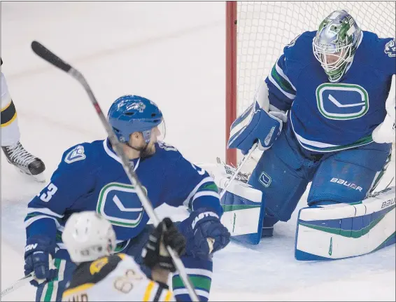 ?? — THE CANADIAN PRESS ?? Boston forward Brad Marchand sends a shot past Vancouver goalie Jacob Markstrom while Canucks defenceman Alexander Edler tries to defend during the first period Saturday night.