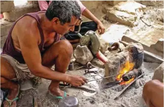  ??  ?? Yemenis burn wood to create a fire to reform metal salvaged from fallen rockets.