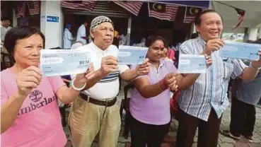  ?? PIC BY HAIRUL ANUAR RAHIM ?? People showing their BR1M vouchers at the BR1M collection ceremony in Johor Baru on Friday.