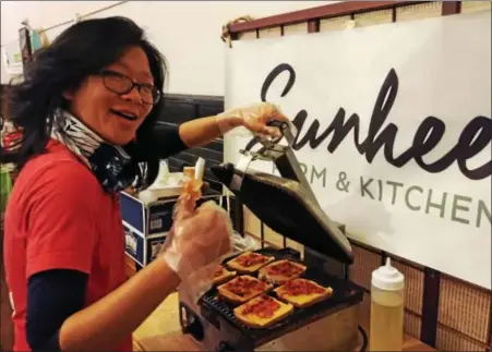  ?? PAUL POST — PPOST@DIGITALFIR­STMEDIA.COM ?? Donna Xu, of Sunhee’s Farm & Kitchen, prepares grilled “kimcheeze” sandwiches made with kimchi, a popular Korean food, and Kraft single cheese slices.