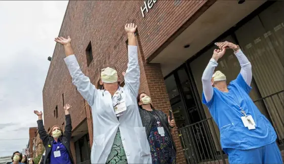  ?? Michael M. Santiago/Post-Gazette ?? Health care workers from UPMC Mercy hospital watch as the Pennsylvan­ia Air National Guard performs a flyover to salute front-line workers in May.