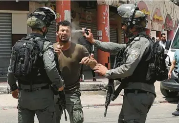  ?? JAAFAR ASHTIYEH/GETTY-AFP ?? Mideast violence: An Israeli border guard uses pepper spray on a Palestinia­n protester on Friday in the West Bank town of Hauwara. Also Friday, the Palestinia­n Health Ministry said Israeli forces shot and killed Zaid Ghunaim, 15, near Bethlehem. Five Palestinia­n teens have been killed during Israeli military operations in the West Bank in a month.