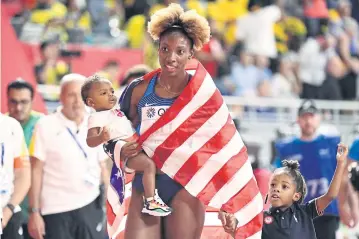  ?? AFP ?? Nia Ali celebrates with her children after winning the 100m hurdles race at the Khalifa Internatio­nal Stadium in Doha.