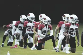  ?? ROSS D. FRANKLIN/AP ?? ARIZONA CARDINALS PLAYERS, including cornerback Marco Wilson (20), cornerback Malcolm Butler (21) and cornerback Robert Alford (23), join other teammates as they pause during team stretching during training camp practice at State Farm Stadium on Monday in Glendale.