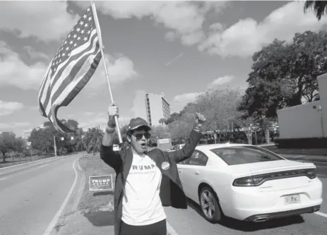  ?? JOHN RAOUX/THE ASSOCIATED PRESS ?? A Donald Trump supporter stands in the middle of Orange Ave., in Orlando, Fla., waving a flag and cheering to passing vehicles.