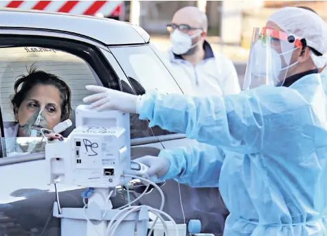  ??  ?? First aid is given to a coronaviru­s patient arriving by car at the emergency department of the Cotugno infectious hospital in Naples