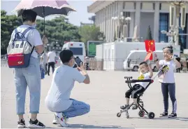  ?? AP ?? Children hold Chinese flags as they pose for a photo at Tiananmen Square in Beijing. China will now allow couples to have a third child as the country seeks to head off a demographi­c crisis that threatens its hopes of prosperity and global influence.