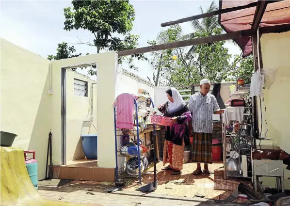  ??  ?? In a mess: Hasanah and her husband Ahmad Murad, 68, surveying the damage after her kitchen roof was blown away at Kampung Tok Sibil, Tajar, Kedah.