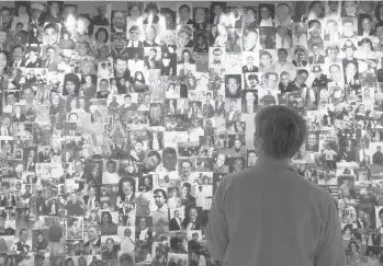  ?? MARK LENNIHAN/AP ?? Désirée Bouchat, who was on the 101st floor of the south tower at the World Trade Center on Sept. 11, 2001, looks at photograph­s in a display at the 9/11 Tribute Museum in New York of those who died. She leads tours at the museum.