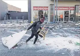  ?? Photo: Marco Longari/afp ?? Aloota continua: A person carries items outside a Vosloorus mall that was vandalised during the July riots.