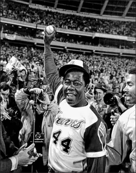  ?? ?? Braves slugger Hank Aaron holds aloft his historic home run ball, which will be on display at Truist Park on Monday.