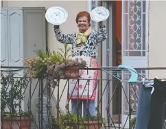  ?? ANDREAS SOLARO / AFP via Gett y Images ?? A woman uses pot lids for cymbals as she takes part in the music flash mob “Look out from the window, Roma mia!”