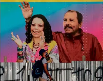  ??  ?? ABOVE: A man walks by a Managua mobile health clinic displaying a picture of Nicaragua’s President Daniel Ortega and his wife Vice-President Rosario Murillo against a backdrop with a cheerful Sai Baba-inspired colour scheme.