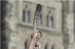  ?? ADRIAN WYLD THE CANADIAN PRESS FILE PHOTO ?? An eagle feather is held up during a rally to raise awareness about missing and murdered Indigenous women and girls. Meggie Cywink, whose sister was slain in 1994, says families are still waiting to hear what government­s have been doing on the MMIWG file.