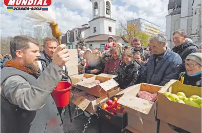  ?? REUTERS ?? Un sacerdote rocía agua bendita a creyentes y comida por la Pascua ortodoxa en Mariupol