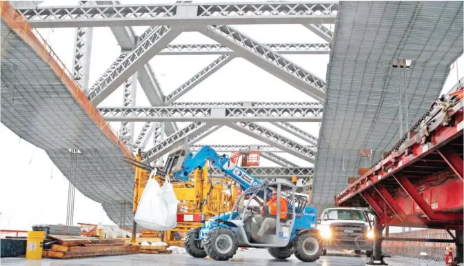  ??  ?? BAYONNE: In this Nov 15, 2016, file photo, a worker lifts materials as constructi­on continues on the new roadway deck of the Bayonne Bridge in Bayonne, NJ. Even as they maneuver for a share of the $1 trillion in spending President-elect Donald Trump...