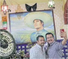  ??  ?? People take a selfie photo next to a painting of iconic Mexican singer and songwriter Juan Gabriel.