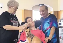  ?? JOLINE GUTIERREZ KRUEGER/JOURNAL ?? Marjorie O’Connell, left, gives daughter Sharla Balestri a drink in their temporary home at a senior living community in Rio Rancho. At right is Rick Marquis, who has been Sharla’s father for nearly 20 years. On Sharla’s lap is Cinco, her service dog.