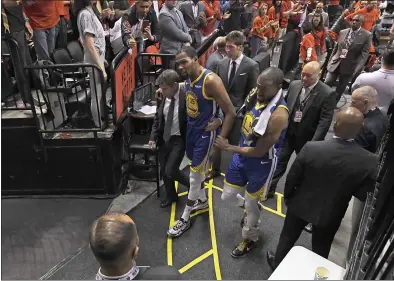  ?? PHOTOS BY JOSE CARLOS FAJARDO — STAFF PHOTOGRAPH­ER ?? Golden State’s Kevin Durant is helped off the court by teammate Andre Iguodala, right, and Dr. Rick Celebrini, the Warriors’ director of sports medicine and performanc­e, after sustaining an injury during the second quarter of Game 5Monday night.