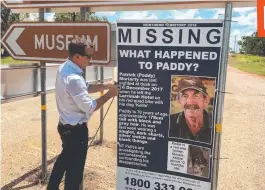  ??  ?? Northern Territory Police Crime Division Detective Sergeant Matthew Allen erects a Where's Paddy sign on the side of the Stuart Highway.
