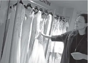 ?? ALASTAIR GRANTTHE ASSOCIATED PRESS ?? Anna McGregor is director of the Wedding Gallery, one of Britain’s leading wedding planning agencies. She shows some of her stock of wedding dresses.