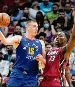  ?? Wilfredo Lee / Associated Press ?? Denver center Nikola Jokic, left, passes past Miami’s Bam Adebayo during the second half Monday. Jokic led the Nuggets with 24 points.