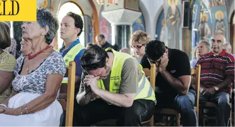  ?? YORGOS KARAHALIS / THE ASSOCIATED PRESS ?? Hundreds of Greek Orthodox faithful attend a memorial service for wildfire victims at a church in the village of Mati, east of Athens, on Sunday. Out in the sea, dozens of volunteer divers searched for the bodies of more possible victims.