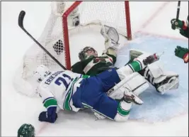  ?? The Associated Press ?? WILD COLLISION: Minnesota Wild goalie Alex Stalock (32) is crashed into by Vancouver Canucks’ Loui Eriksson (21) during the second period of Thursday’s NHL playoff game in Edmonton, Alberta.