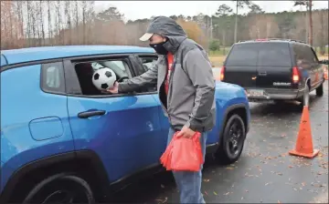  ?? Courtesy of Jim Alred ?? Rick Haase hands a soccer ball to a child during the RFPRA’S Drive Thru Playtime with Santa event on Dec. 12, 2020 at Ridge Ferry Park.