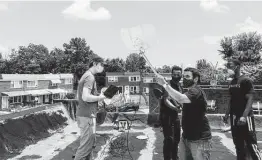  ?? New York Times file photo ?? Adam Bouhmad, second from right, and others set up an antenna for internet access on the roof of a home in Baltimore last June.