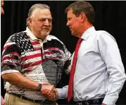  ?? CHRISTINA MATACOTTA / CHRISTINA.MATACOTTA@AJC.COM ?? Cobb Sheriff Neil Warren greets Gov. Brian Kemp during the Corn Boilin’ on July 15, when 85 sheriff’s office employees were on leave the day of the event, according to county records.