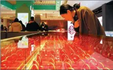  ?? WANG JIANKANG / FOR CHINA DAILY ?? A shopper looks at gold ornaments at a jewelry store in Suzhou, Jiangsu province.