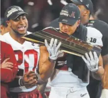  ?? Getty Images ?? Alabama defensive back Minkah Fitzpatric­k checks out the College Football Playoff championsh­ip trophy Monday night in Atlanta, where the Tide beat Georgia in OT.