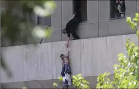  ?? AP PHOTO/FARS NEWS AGENCY, OMID VAHABZADEH ?? A man hands a child to a security guard from Iran’s parliament building after an assault of several attackers in Tehran, Iran on Wednesday. Suicide bombers and gunmen stormed into Iran’s parliament and targeted the shrine of Ayatollah Ruhollah Khomeini...