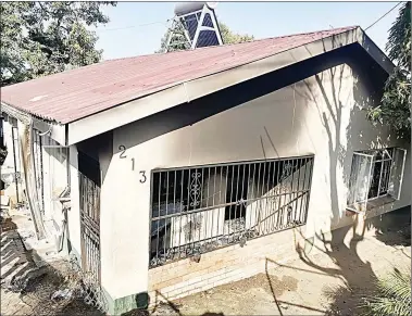  ?? ?? THE FRONT VIEW OF THE SENIOR POLICE OFfiCER’S HOUSE WHICH WAS TORCHED BY UNKNOWN ARSONISTS YESTERDAY, AFTER 8AM AT TWO STICKS, MANZINI. THE fiRE LEFT DAMAGES AMOUNTING TO ABOUT E15 000. (R) TWO POLICE OFfiCERS WHO WERE WEARING BULLETPROO­F VESTS WERE PICTURED ARRIVING AT THE SCENE.