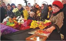  ?? AP ?? ■ Relatives of victims of the mall fire lay flowers on their coffins during a mourning ceremony in a church in Kemerovo.