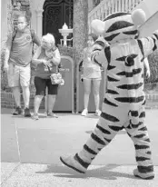  ?? JOE BURBANK/ORLANDO SENTINEL ?? Tigger entertains guests wearing masks as required to attend the official reopening day of the Magic Kingdom. A man was charged with hitting a Disney guard when he was reminded to follow the theme park’s mask rules.