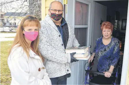  ?? SHARON MONTGOMERY • CAPE BRETON POST ?? Jim Kronlund of North Sydney and volunteer Lisa Pelland, left, drop off books to Carole Smith of Glace Bay, who has mobility issues and difficulty getting out, as part of the new Capers Community Books Facebook volunteer group Kronlund started. Kronlund said anyone can stop by his house on Stanley Street in North Sydney to sign out a book.