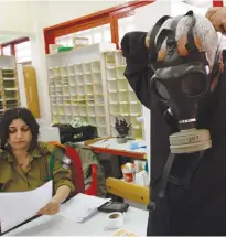  ?? (Gil Cohen Magen/reuters) ?? A MAN tries on a gas mask in Tel Aviv last year. Only about 60% of Israelis have one.