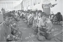  ??  ?? RESCUED MIGRANTS
A group of Rohingya migrants from Myanmar waits for their meal from Indonesian volunteers at the confinemen­t area in the fishing port of Kuala Langsa in Aceh province on May 18, 2015, where hundreds of migrants from Myanmar and...