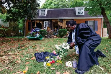  ?? (AP Photo/Nell Redmond) ?? The Rev. Raymond Johnson, of Marion, S.C., arranges flowers Tuesday on the lawn of the home on Galway Drive in Charlotte, N.C., where a shootout between a suspect and officers occurred during an attempt to serve a warrant on Monday. Four law enforcemen­t officers were killed.