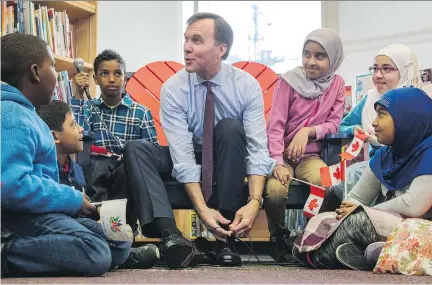  ?? MARK BLINCH/THE CANADIAN PRESS ?? Finance Minister Bill Morneau takes part in the pre-budget ceremony of putting on new shoes at Nelson Mandela Park Public School in Toronto on Monday. Morneau says the budget will introduce “new measures that will be important for Canadian families.”