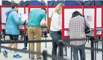  ?? JOHN MINCHILLO / AP ?? GETTING A HEAD START: Voters fill out their ballots at the Hamilton County Board of Elections in Cincinnati on Wednesday on the first day of early voting in Ohio.