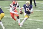  ?? Matt Cashore / Associated Press ?? Notre Dame quarterbac­k Ian Book (12) runs as Syracuse defensive lineman Jonathan Kingsley pursues in the first half on Sunday in South Bend, Ind.
